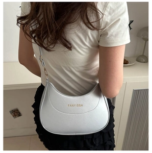 Détail d'un sac hobo gris avec logo doré et bandoulière ajustable pour un style élégant