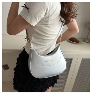 Close-up of a light blue crescent bag with gold FANYISSA logo on a white T-shirt