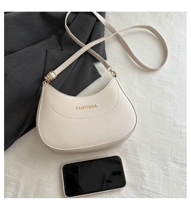 Détail du sac hobo en croissant crème avec logo doré et bandoulière réglable pratique