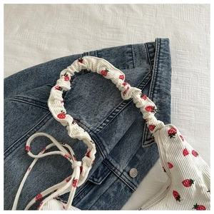 Detalle del bolso de pana blanca con estampado de fresas y correa fruncida