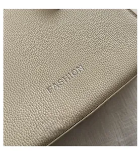 Macro shot of beige lychee pattern leather detail with silver FASHION embossing