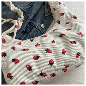 Detalle del bolso de pana blanco con estampado de fresas y diseño de asa fruncida suave