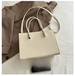 Detail of cream rectangular handbag with lychee texture leather and fashion logo