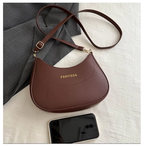 Sac demi-lune marron foncé à côté d'un smartphone pour comparer la taille réelle