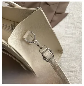 Detail of silver metal hook and premium lychee texture leather on a beige tote bag