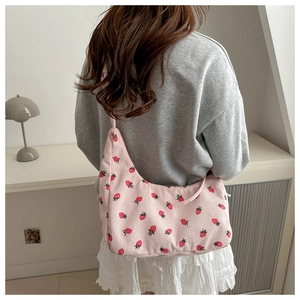 Primer plano de bolso media luna en pana rosa con estampado fresas sobre modelo