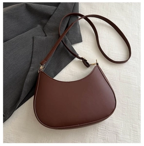 Gros plan d'un sac demi-lune marron foncé en similicuir lisse avec ferrures dorées
