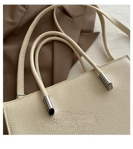 Close-up of dual top handles on a cream leather tote with polished silver hardware