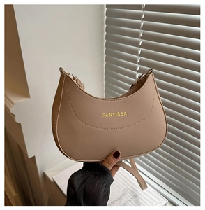 Détail du sac beige en demi-lune avec chaîne dorée et logo FANYISSA gravé