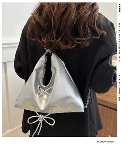 Detail of silver metallic tote bag with stylish chain strap and ribbon decoration
