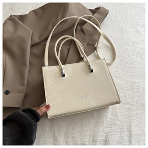 Detailed macro of a cream white leather handbag with elegant metallic handle accents