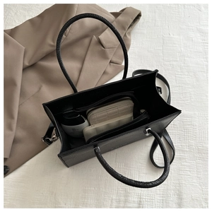 Spacious interior of a black faux leather tote bag with wallet and makeup accessories
