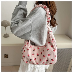 Detalle de bolso bandolera de pana rosa con estampado de fresas y correa con volantes