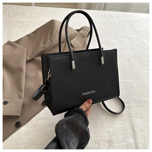 Detail of black pebbled leather handbag with silver Fashion logo and elegant handle
