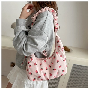 Close-up of pink corduroy shoulder bag with strawberry print and ruffled strap detail
