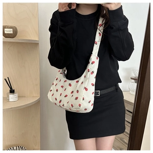 Detalle de bolso de hombro de pana crema con bonitos estampados de fresas rojas
