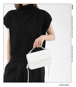 Close-up of white quilted crossbody bag with diamond stitching and elegant top handle