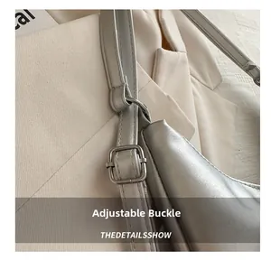 Detail of adjustable metal buckle on stylish silver tote bag with leather straps