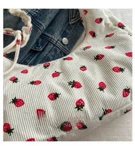 Detailed view of the strawberry print on corduroy fabric of a beige shoulder bag