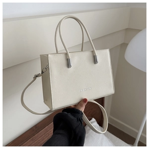 Detail of cream-white lychee textured leather tote bag with silver FASHION lettering