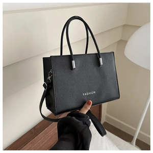 Close-up of black lychee texture tote bag with white fashion print and silver hardware