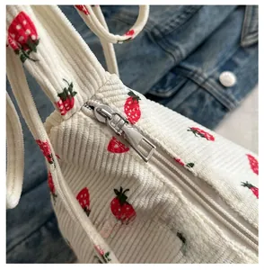 Close-up of smooth silver metal zipper on cream corduroy tote with strawberry print
