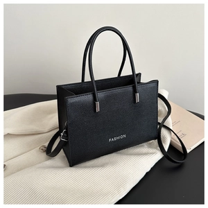 Detail of black lychee grain leather tote bag with white fashion text and silver hardware