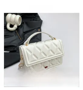 Detailed close-up of white quilted faux leather handbag with gold hardware and strap