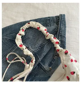 Detail of white corduroy shoulder bag with strawberry print and ruched elastic handle