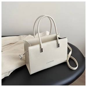 Close-up of beige tote bag featuring pebbled leather texture and FASHION embossed logo