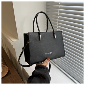 Close-up of black lychee grain leather handbag with silver hardware and FASHION logo