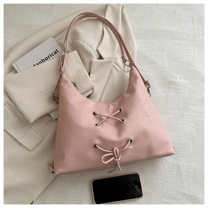 Pink bow shoulder bag with cross-lace detail styled with blazer and book for lifestyle