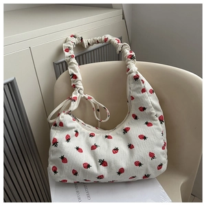 Detalle de bolsa de pana blanca con estampado de fresas sobre una silla beige