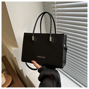 Detail of black pebbled leather tote bag with FASHION logo and silver hardware