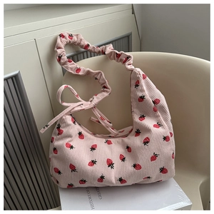Detalle del bolso de pana rosa con estampado de fresas y lazo lateral decorativo