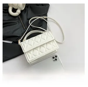 Detail of white quilted crossbody bag showing texture and size compared to a phone