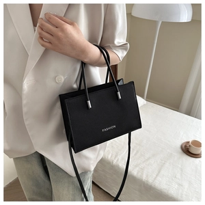 Detail of black pebbled leather handbag featuring white FASHION text and silver hardware