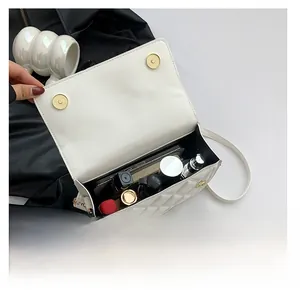 Detailed interior storage view of white quilted crossbody bag with items inside