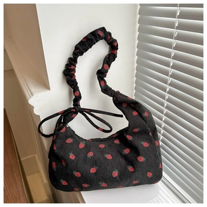 Detalle de bolso de hombro de pana negra con estampado de fresas y lazo fruncido