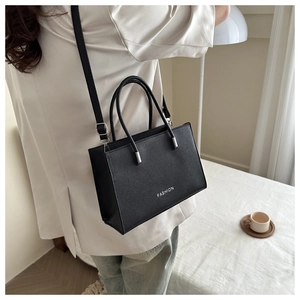 Close-up of black lychee grain faux leather tote bag with FASHION text and long strap