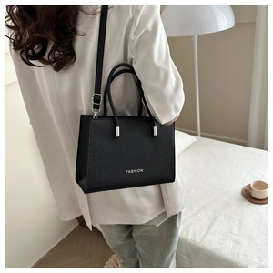 Close-up of black lychee grain tote bag showing fashion print and detachable strap