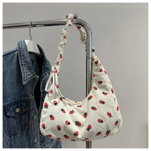 Detalle de bolso de pana con estampado de fresas y textura de asa fruncida