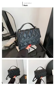 Detail of black quilted crossbody bag with golden hardware and glossy leather finish