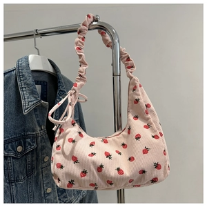Detalle de textura de pana rosa del bolso hobo con estampado de fresas y lazo lateral