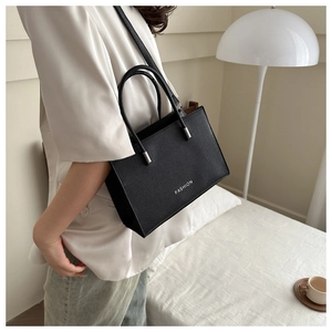 Detailed view of the black lychee pattern leather handbag with fashion text and shoulder strap