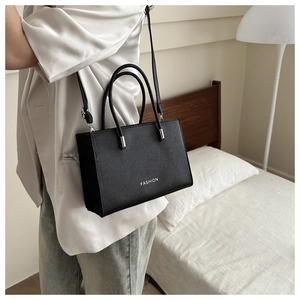 Detail of black pebbled leather tote bag with white Fashion lettering and silver hardware