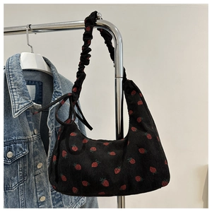 Detalle de bolso hobo de pana con estampado de fresas y correas plisadas con lazos