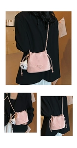 Detail of pink drawstring bucket bag with metal chain strap and plush monster charm
