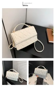 Detail of white quilted crossbody bag with gold hardware and removable shoulder strap