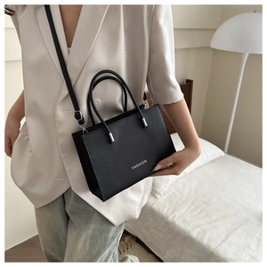 Detail of black pebbled leather tote bag with FASHION logo and removable shoulder strap